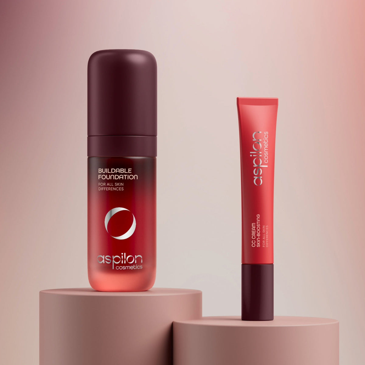 Aspilon Buildable Foundation bottle and CC Cream tube standing on beige pedestals against a soft pink background
